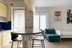 Una cucina moderna con un tavolo da pranzo, sedie, un divano e un'opera d'arte appesa al muro.