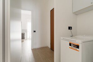 A laundry room with a washing machine, a door leading to another room, and a light switch on the wall. - Comfortable 40m2 studio flat, ideal for 3 people, located on the third floor of a building with lift.The accommodation is located a stone's throw from Famagusta, characterized by a strong residential and student vocation, offering a quiet environment, gr (Milan)