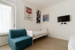 A room with a teal sofa, a white bed, a TV, and two posters on the wall. - Comfortable 40m2 studio flat, ideal for 3 people, located on the third floor of a building with lift.The accommodation is located a stone's throw from Famagusta, characterized by a strong residential and student vocation, offering a quiet environment, gr (Milan)