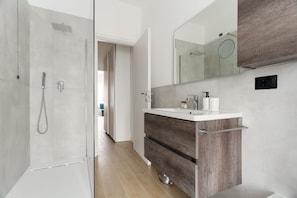 Un bagno moderno con doccia, un mobile lavabo con specchio e un armadietto in legno.