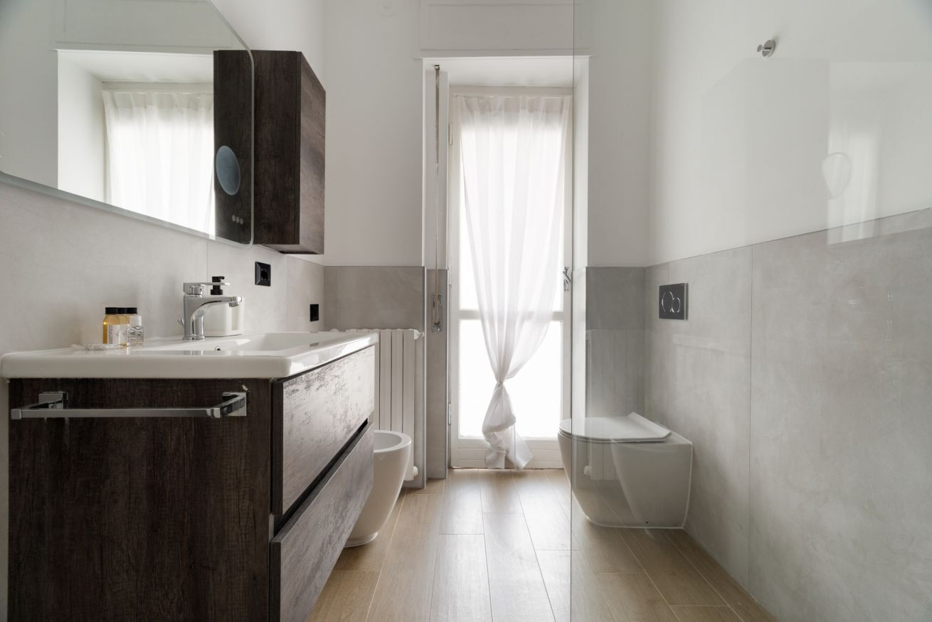 A modern bathroom with a wooden vanity, a toilet, and a shower area.