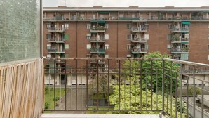 Een meerlaags woongebouw met balkons, een houten hek en een kleine tuin.