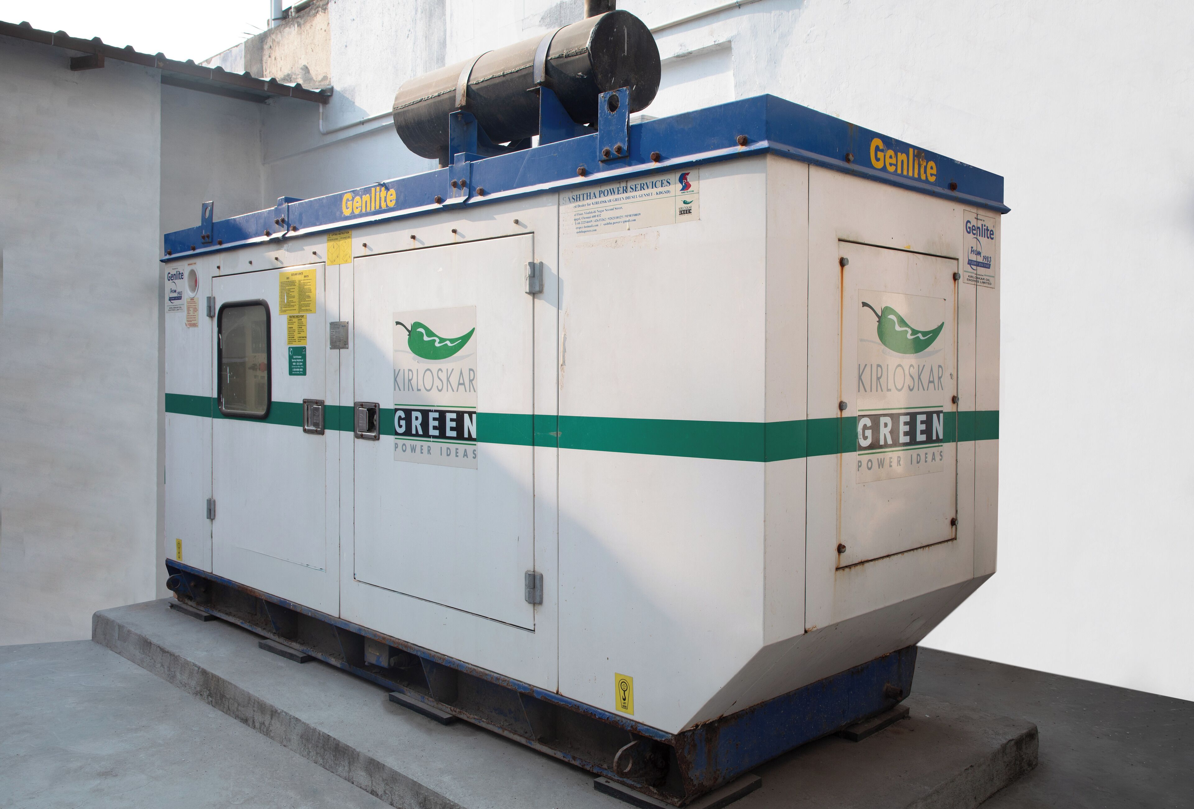 Una máquina industrial grande con la marca 'Genlite' y 'KIRLOSKAR GREEN POWER IDEAS', montada sobre una plataforma de hormigón.