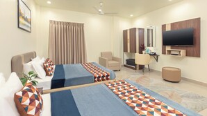 A hotel room with two beds, a TV, a desk, and a chair. - Greens Venue (Chennai)