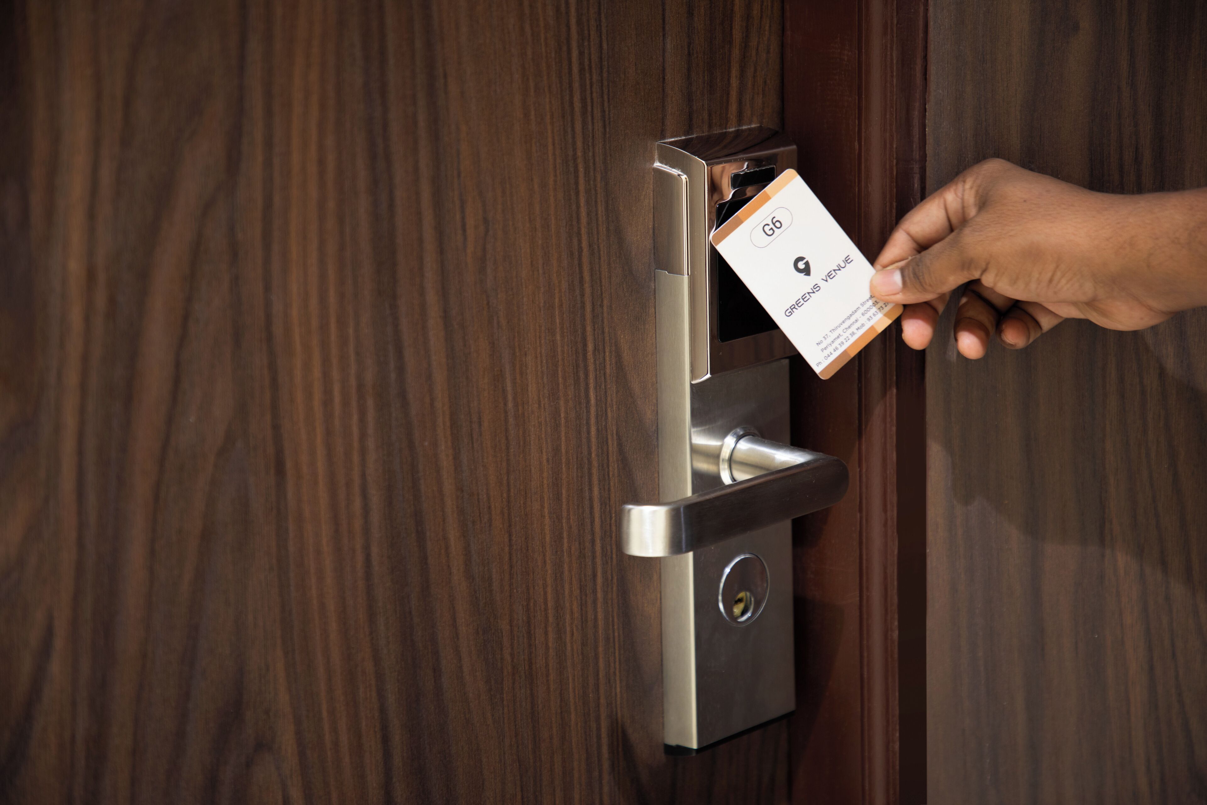 A hand inserting a key card into a modern door lock.