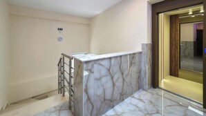 Ein modernes Badezimmer mit Marmorwaschtisch, Duschabtrennung aus Glas und sichtbarer Toilette.