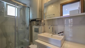 Ein modernes Badezimmer mit einer Glasdusche, einem weißen Waschbecken mit Spiegel darüber und einer Toilette mit Handtuch darauf.
