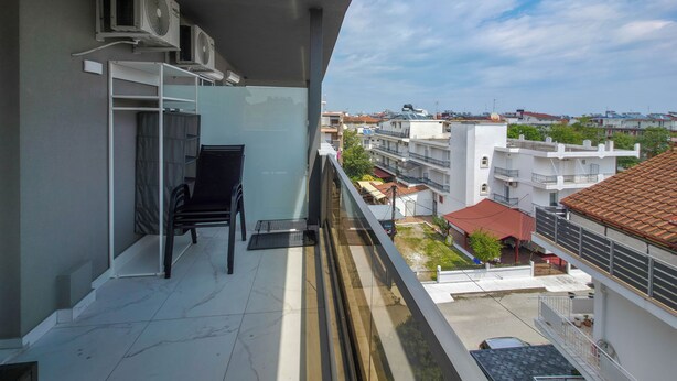 Ein Balkon mit Stuhl, Klimaanlagen und Blick auf die Stadtlandschaft.