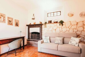 Ein Wohnzimmer mit Steinwand, Kamin, einer Couch und einem Schreibtisch mit Stuhl.