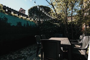 An outdoor patio with a table and chairs, string lights, and a tiled wall. - La casa di Solcio  - Lakeside L&B (Lesa)