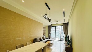 Un salon moderne avec un coin repas, de grandes fenêtres et un ventilateur de plafond.