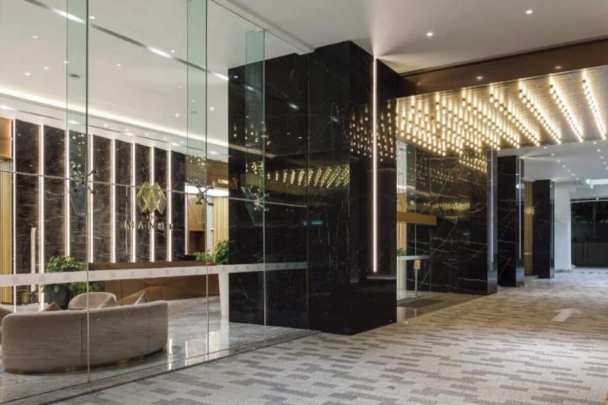 A modern lobby with glass partitions, a black marble column, and a patterned carpet.