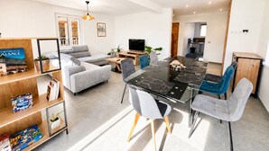 A modern living room with a dining table, sofas, a TV, and a kitchen area. - High Standing Contemporary House - 4 Bedrooms, Terrace & Green Space (Wingersheim les Quatre Bans)
