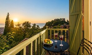Ein Balkon mit Tisch, zwei Weingläsern und einer Obstschale.