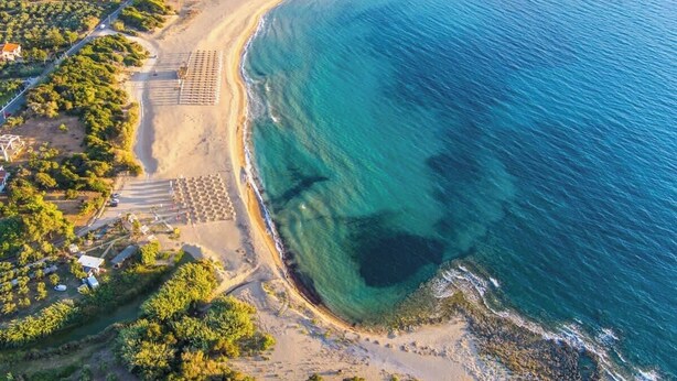 Ett flygbildsbild av ett kustområde med en strand, en väg och en vingård.