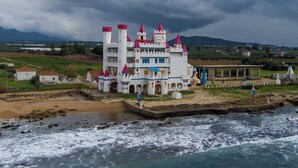 Un edificio al estilo de castillo con múltiples torres, ubicado junto a una masa de agua.