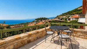 A terrace with stone walls, a round table, and chairs overlooking a coastal village. - Kyparissia Aries Stone Maisonette, Panoramic Views (Kiparissia)