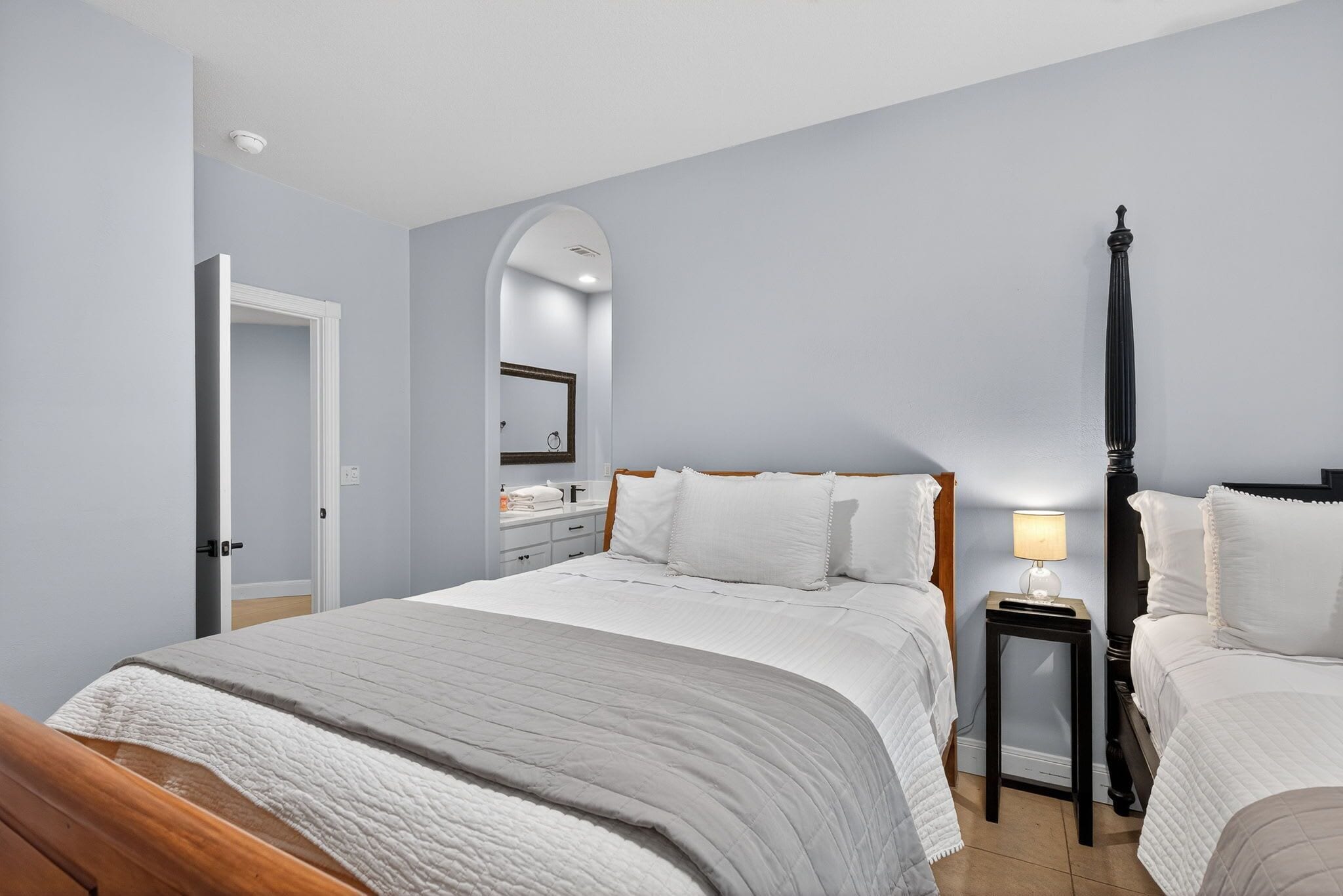 A bedroom with a bed, bedside tables, a mirror, and a door.