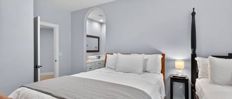 A bedroom with a bed, bedside tables, a mirror, and a door.