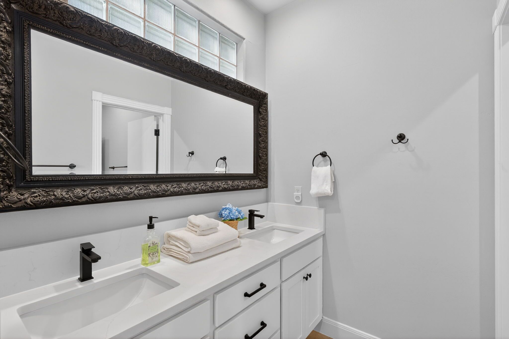 A bathroom with two sinks, a large mirror, and a towel rack.
