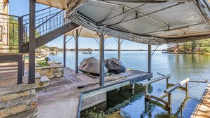 Un muelle cubierto con una escalera que lleva a una zona de piscina, rodeado de aguas tranquilas y edificios lejanos.