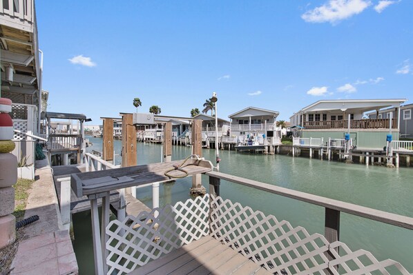 A waterfront property with multiple docked boats, a wooden deck, and a view of the water.