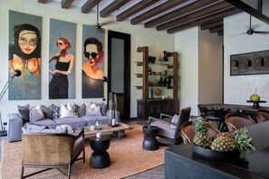 Uma sala de estar moderna com sofá, mesa de centro e cadeiras, uma área de jantar com mesa e cadeiras, e uma estante com objetos decorativos.