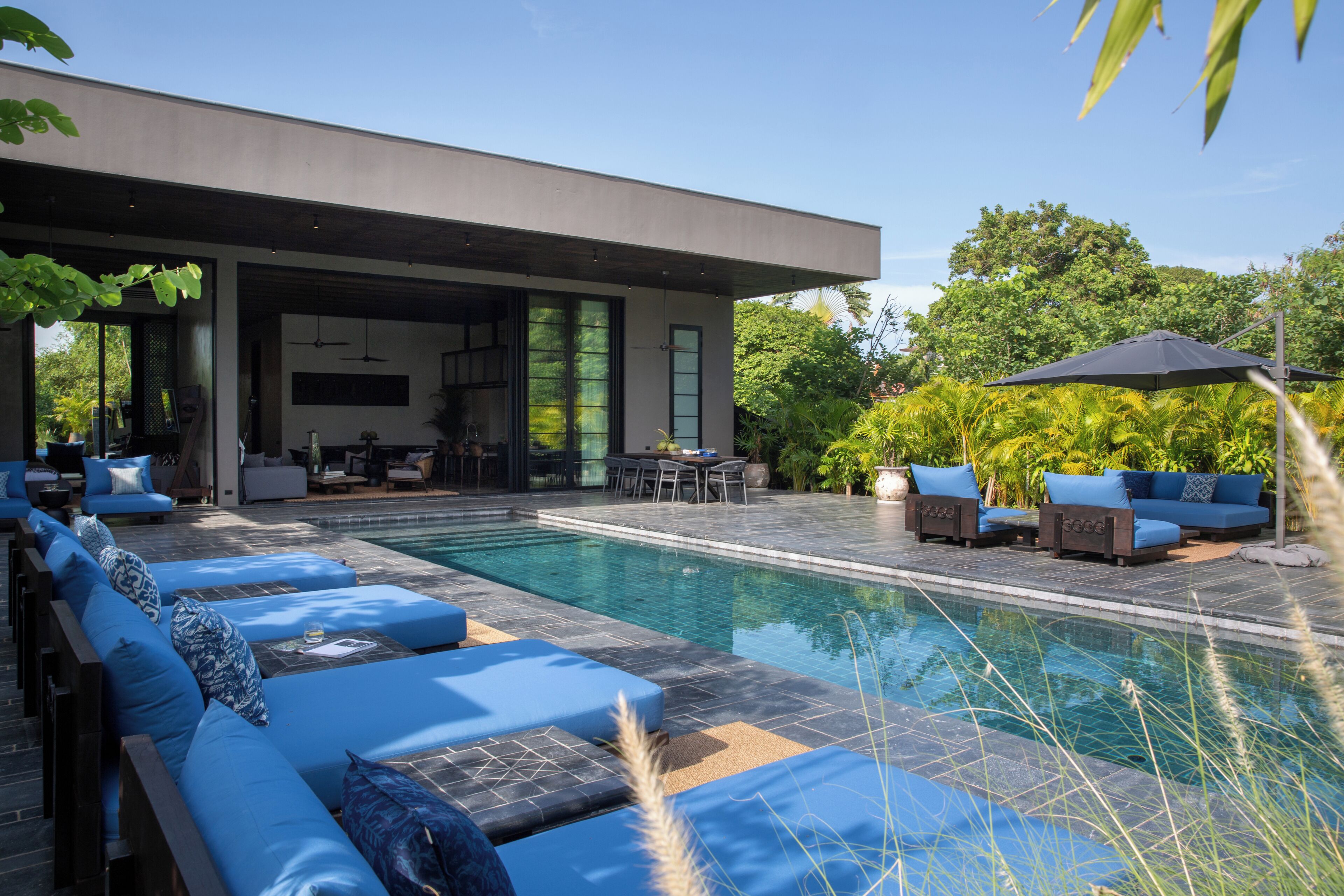 A modern house with a swimming pool, outdoor seating, and lush greenery.