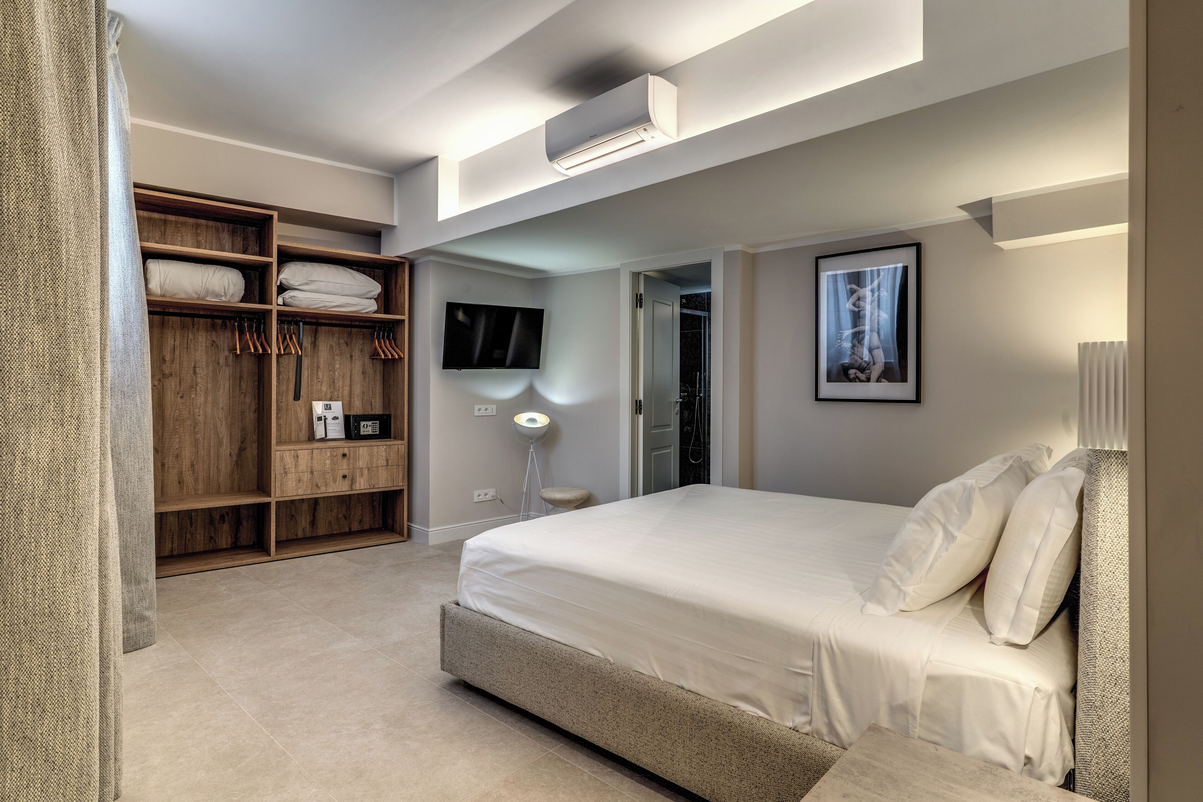 A bedroom with a bed, a wardrobe, a TV, and a bedside lamp.