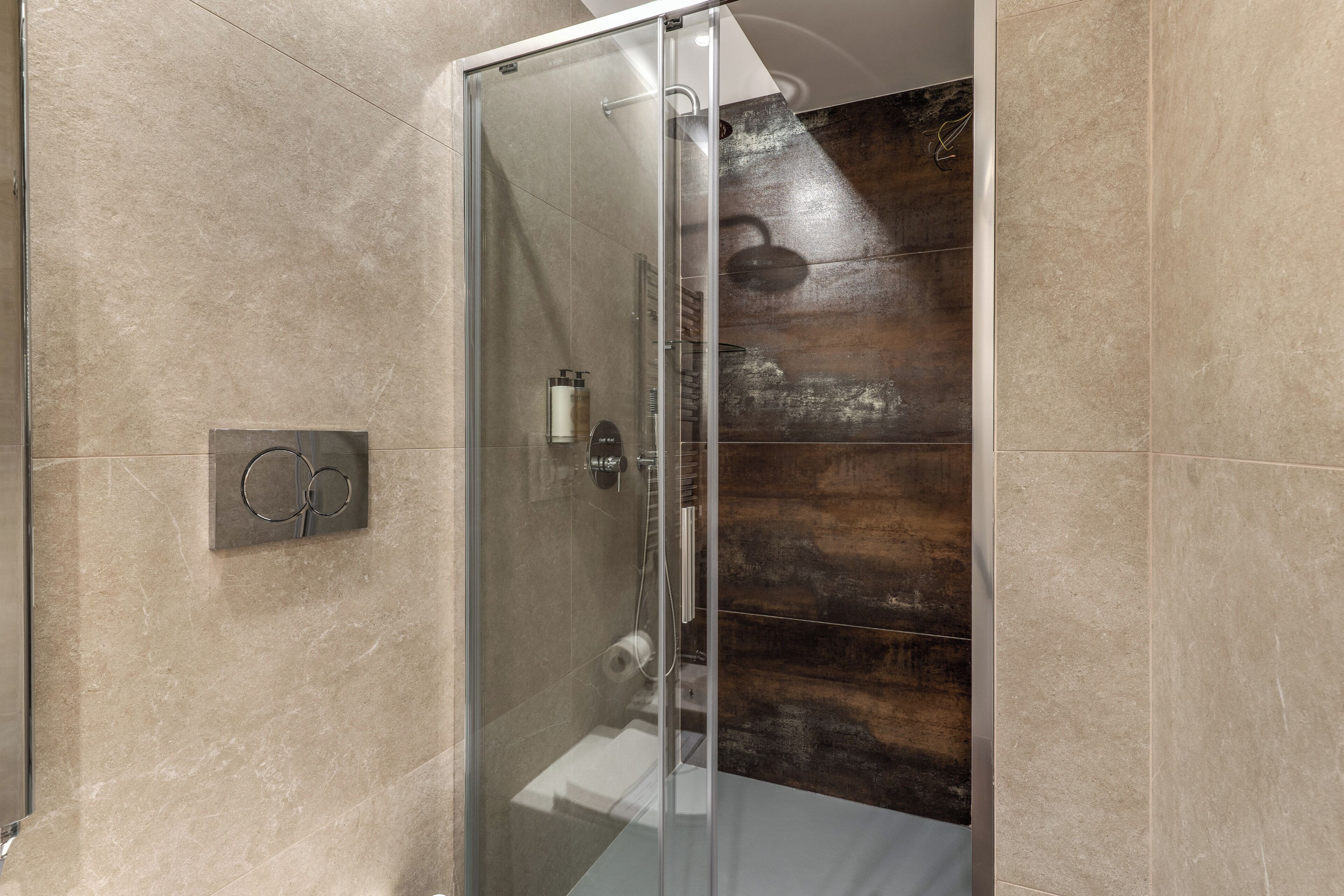 A glass-enclosed shower with a wooden wall panel, a towel rack, and a control panel.