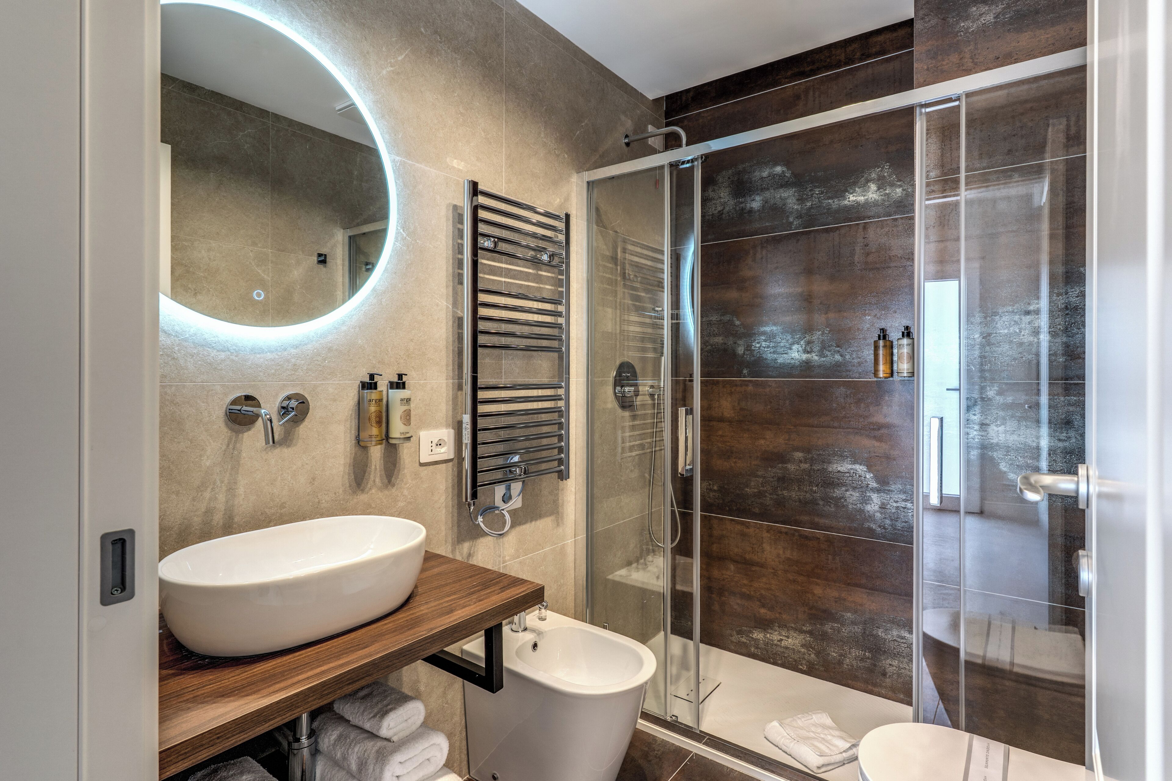 Ein modernes Badezimmer mit einem großen, ovalen Waschbecken, einer Duschkabine aus Glas und einem Holzbadezimmermöbel.