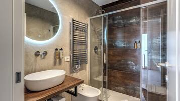 Ein modernes Badezimmer mit einem großen, ovalen Waschbecken, einer Duschkabine aus Glas und einem Holzbadezimmermöbel.