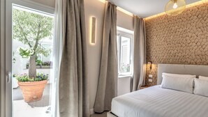 A bedroom with a bed, curtains, a wall-mounted light, and a window with a view of a tree and flowers. - LF Borgo Trastevere (Rome)
