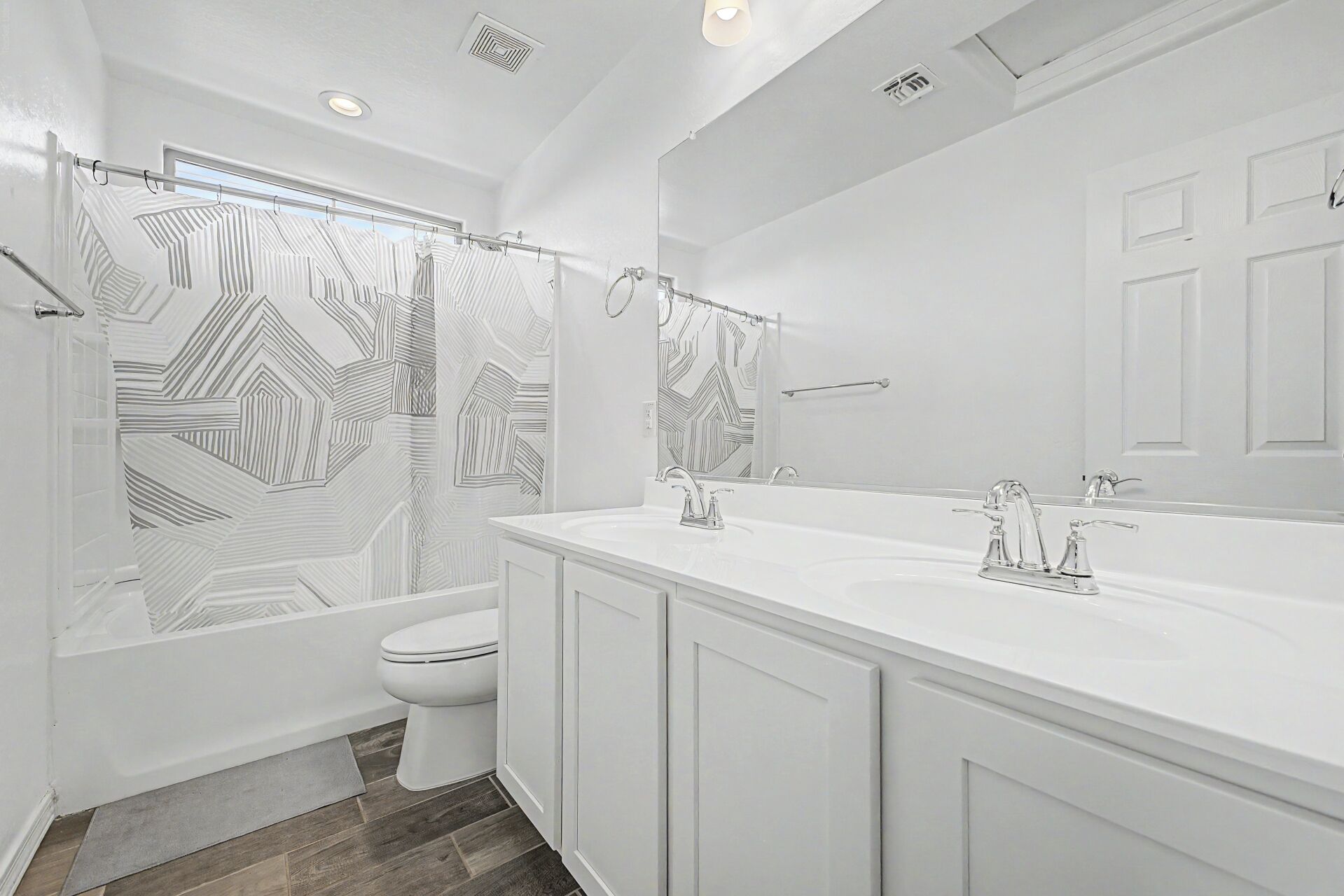 A modern bathroom with a shower, toilet, and a large vanity with a mirror.