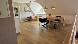 Un loft espacioso con comedor, piso de madera y techo alto.