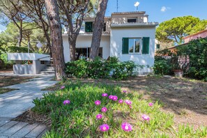 A modern two-story house with a garden in front, surrounded by trees. - Villa Montecristo - Diadema di Venere (Marina di Campo)