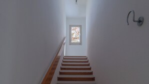 Eine Treppe mit Holzstufen und Handlauf, die zu einer Tür mit Fenster führt.