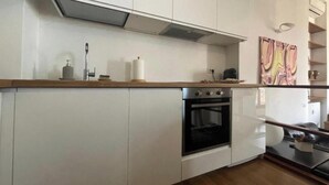 Una cocina moderna con armarios blancos, encimera de madera, horno empotrado y un lavamanos de pared.