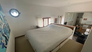 Un dormitorio con cama, escritorio, silla y ventana con cortinas.
