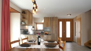 A dining area with a wooden table set for four, a wine bottle, and glasses.
