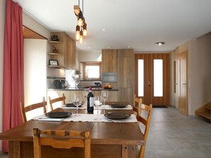 A dining area with a wooden table set for four, a wine bottle, and glasses.