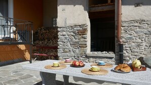 A stone table with placemats, cups, apples, and pastries.