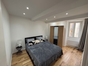 A bedroom with a bed, bedside lamps, a wardrobe, and a window. - Apartment in the center of Vieux Cannet (le cannet)