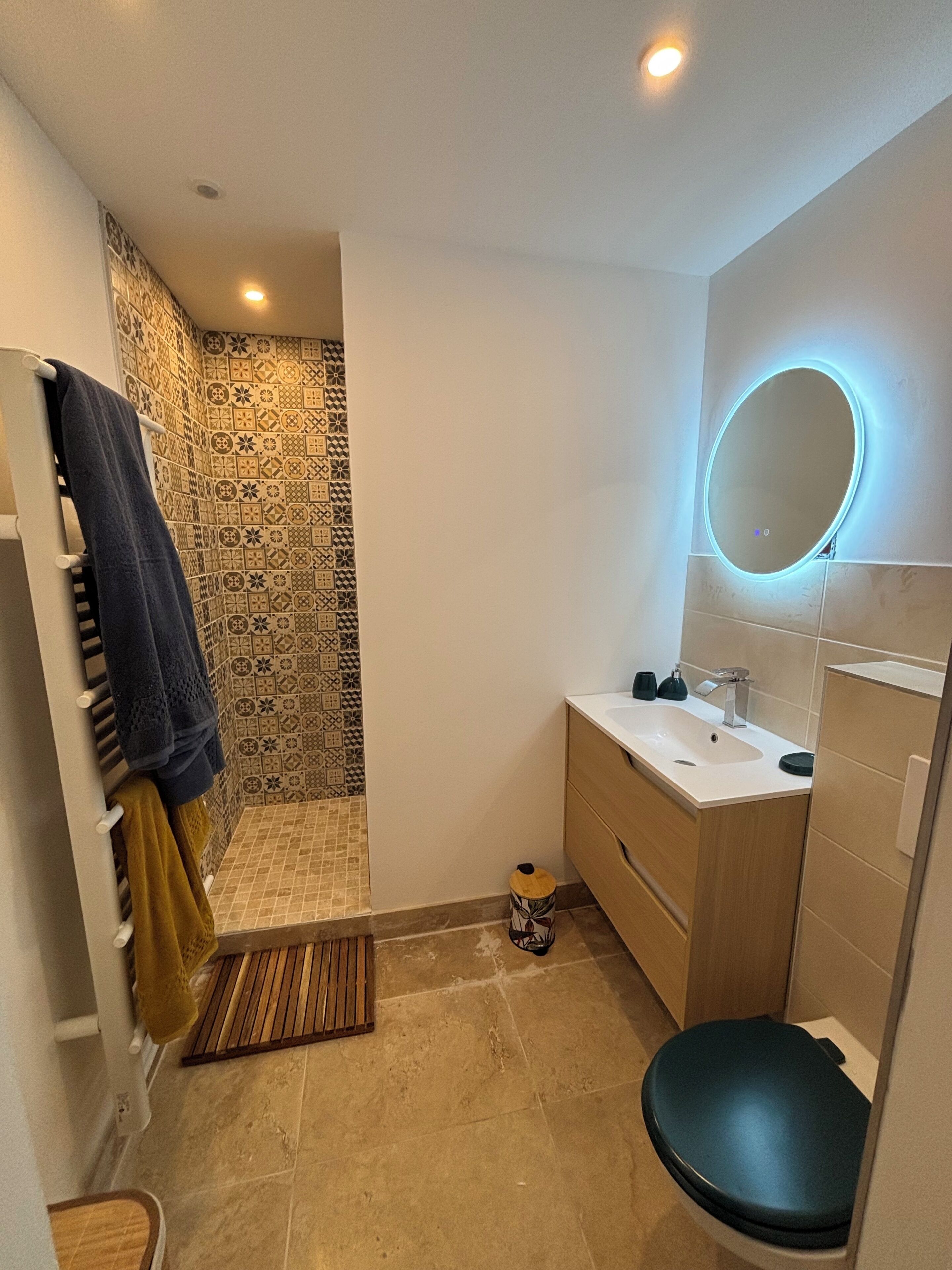 Une salle de bain avec un mur recouvert de carreaux à motifs, un lavabo avec un miroir et des toilettes.