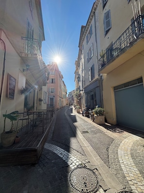 A narrow street with buildings on either side, a manhole cover on the ground, and a clear sky. - Apartment in the center of Vieux Cannet (le cannet)