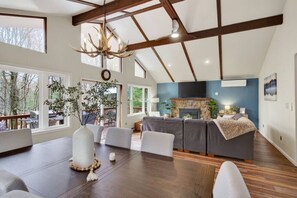 A spacious living area with a dining table, sofas, a fireplace, and large windows. - Hot Tub & Fire Pit • 1 Min to Lake (lake harmony)