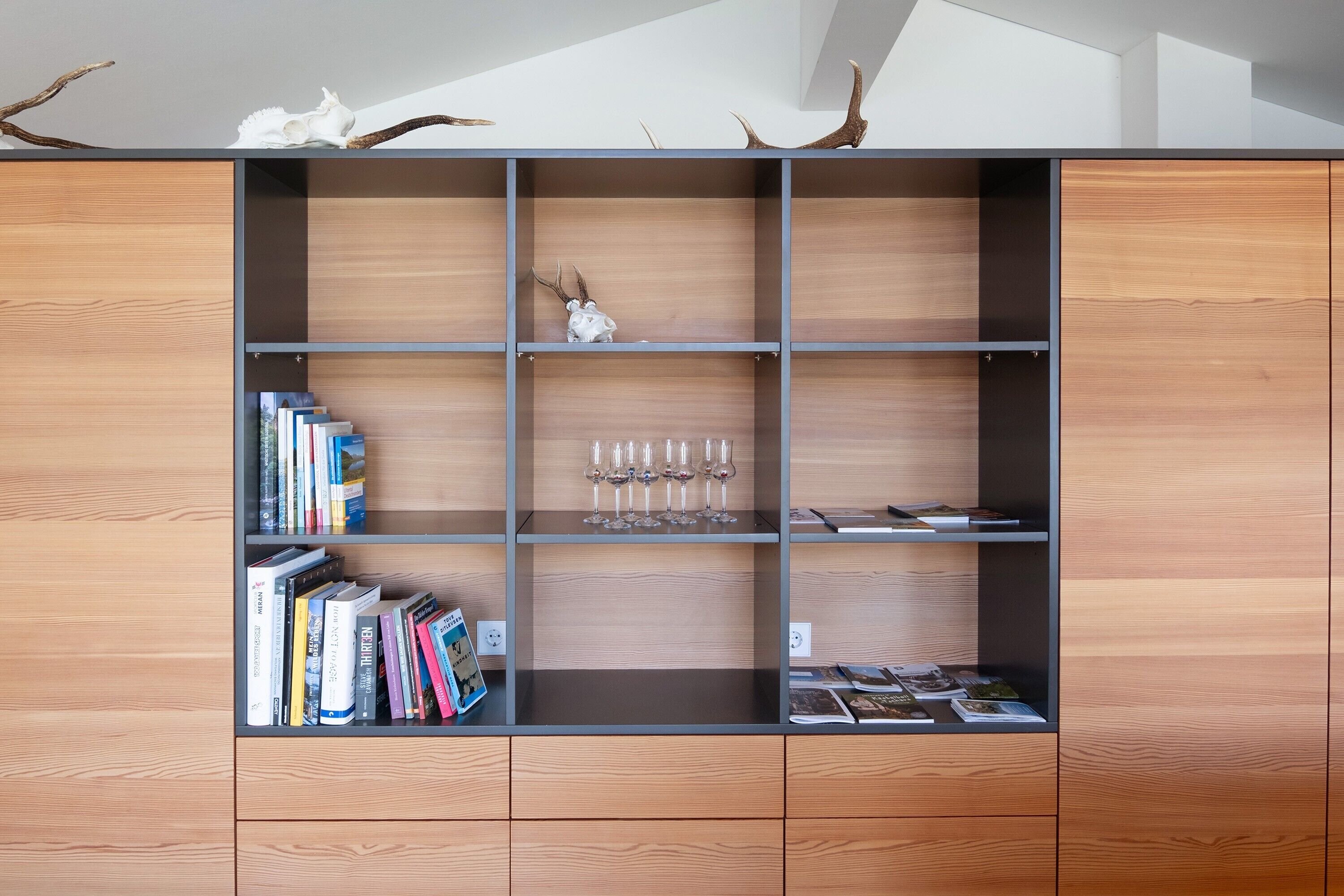 A wooden bookshelf with multiple shelves, some containing books and others with decorative items.