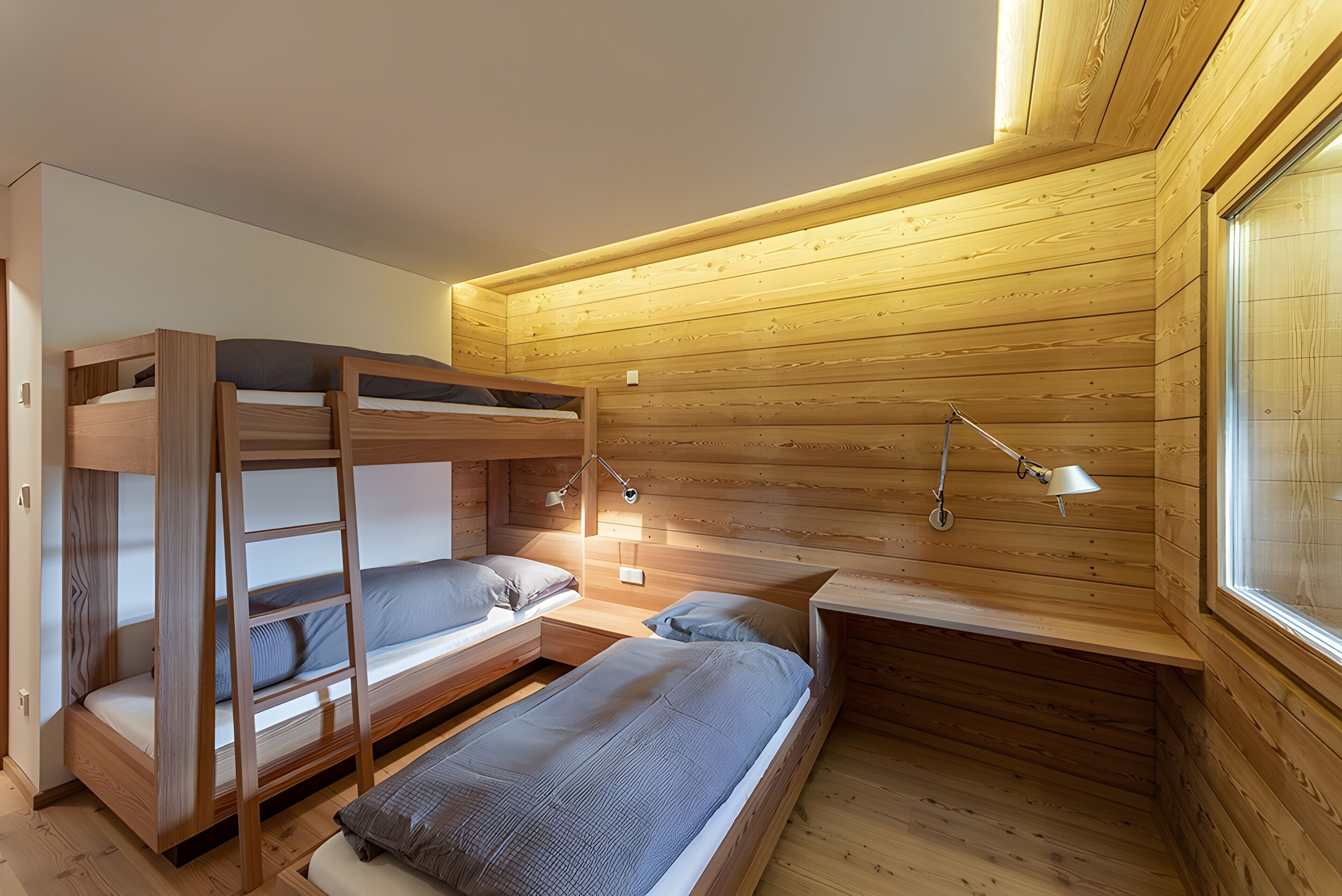 Ein kleines Zimmer mit Etagenbetten, einem Schreibtisch und zwei Nachttischlampen.