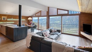 A modern living space with a kitchen, dining area, and a sofa with a view of the mountains. - Chalet Oberjuval – Unique and Stylish Retreat Amidst Alpine Meadows (Castelbello-Ciardes)
