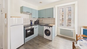 A compact kitchen with a washing machine, a stove, and a sink. - Charming duplex for 2 in the city center (Pont-l´Abbé)